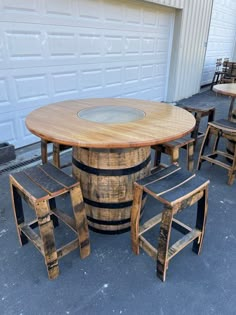 an outdoor table made out of wine barrels and stools is shown in front of a garage door