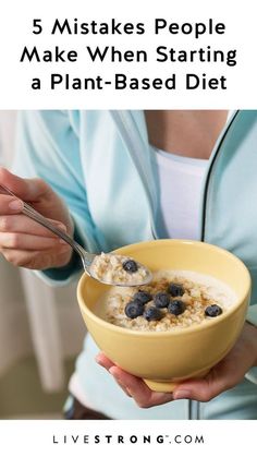 a woman is holding a bowl of oatmeal with blueberries in it