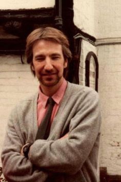 a man with his arms crossed standing in front of a building