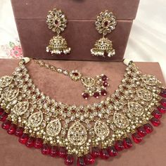 Beautiful antique gold necklace set with dazzling champagne zircon crystals and maroon stones. Plus maroon glass beads. Perfect bridal set Comes with matching jhumka earrings and matching tikka! Necklace 3 inch with adjustable string Earrings 2.25 Inch including jhumka length x 1 inch width Tikka 2.5 inch pendant plus 2 inch chain and 2 inch extender chain  Ready to be shipped ❤️ Festive Crystal Jewelry With Intricate Design, Bollywood Style Wedding Jewelry With Stones, Festive Crystal Jewelry Sets For Wedding, Traditional Crystal Jewelry With Stone Work, Ornate Jeweled Necklaces For Wedding, Celebration Ruby Jewelry With Stone Work, Ornate Jeweled Wedding Necklaces, Festive Crystal Jewelry With Stone Work, Ornate Kundan Jewelry For Party