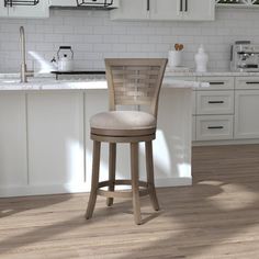 a kitchen with white cabinets and an island in the middle is shown, along with a bar stool