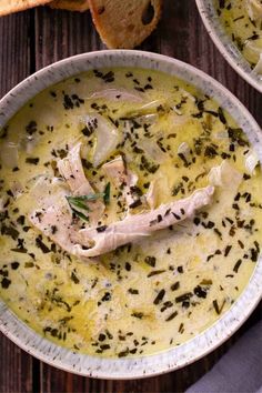 two bowls of soup with bread on the side