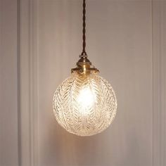 a glass light hanging from a ceiling in a room with white walls and wood trimmings