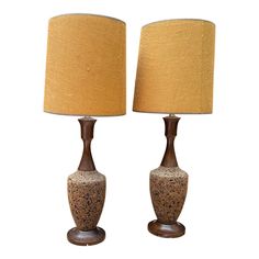 two brown and white ceramic lamps on wooden bases with shades of gold fabric coverings