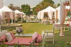 an outdoor wedding venue with pink and white decor on the lawn, covered in draping