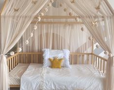 a canopy bed with white curtains and pillows