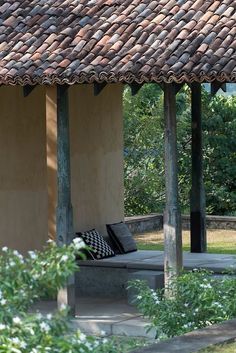 a bench sitting under a thatched roof next to trees