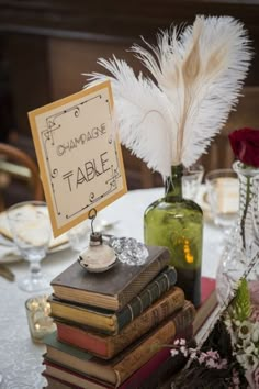 a table topped with lots of books and vases filled with white feathery flowers