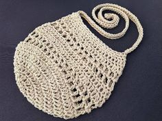 a crocheted bag is sitting on a black surface and it has a white handle