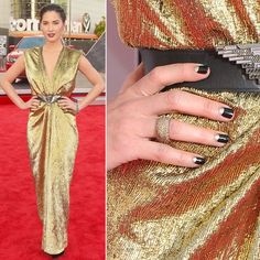 an image of a woman in gold dress with black nails and ring on her finger