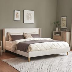 a white bed sitting on top of a wooden floor next to a dresser and chair