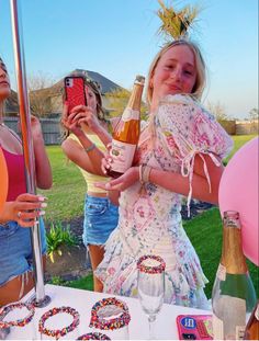 two girls standing next to each other at a table with food and drinks on it