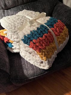 three crocheted blankets stacked on top of each other in front of a couch