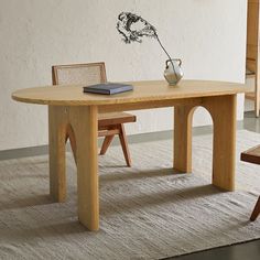 a wooden table with two chairs and a vase on top of it in front of a white wall