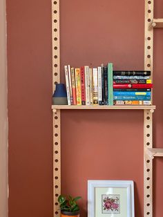 a bookshelf with several books on it next to a small potted plant