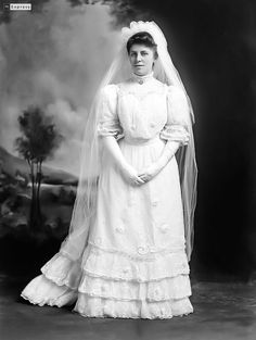 an old black and white photo of a woman in a wedding dress wearing a veil