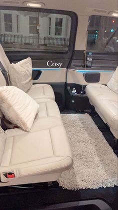 the interior of a vehicle with white leather seats and pillows on it's floor