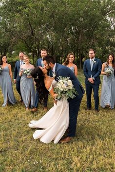 a bride and groom kissing in front of their bridal party on the grass outside