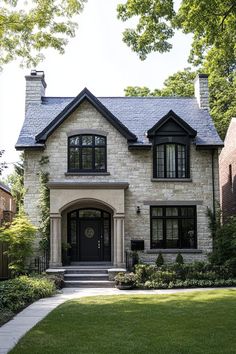 a white brick house with black trim and windows on the front door is surrounded by greenery