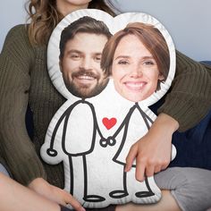 a woman holding a pillow with the image of a man and woman on it in front of her