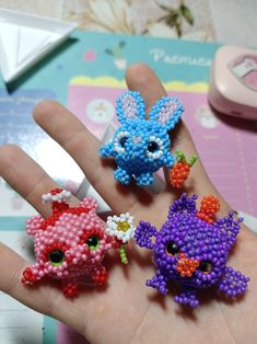 three small beaded animals sitting on top of a person's hand