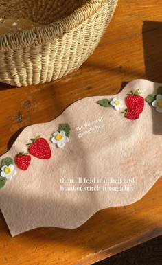 a piece of cloth with strawberries and daisies on it sitting next to a basket