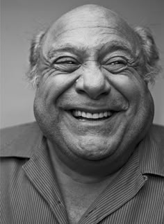 black and white photograph of an older man smiling at the camera with his eyes wide open