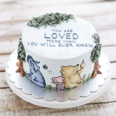 a winnie the pooh birthday cake is decorated with greenery and an inscription that reads, you are loved more than you will ever know