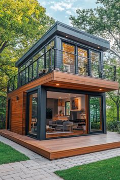 a modern house with wooden decking and glass windows on the top floor, surrounded by trees