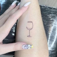 a woman's arm with a wine glass tattoo on the left side of her arm