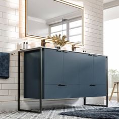 a bathroom with a blue cabinet next to a white brick wall and a mirror on the wall