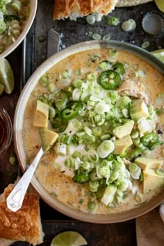 a bowl filled with soup and topped with sliced green onions, jalapenos and cheese