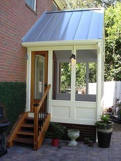 a small house with a metal roof and stairs leading up to the front door area