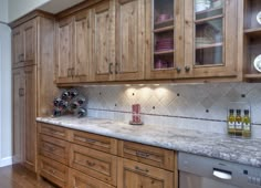 a kitchen with wooden cabinets and marble counter tops, along with wine racks on the wall