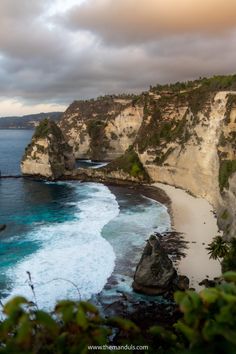 the ocean is blue and white with waves coming in from the rocks on the shore