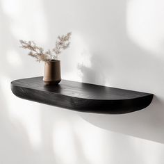 a wooden shelf with a potted plant sitting on it's side, against a white wall