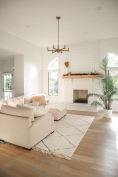 a living room with white couches and a rug on the floor in front of a fireplace