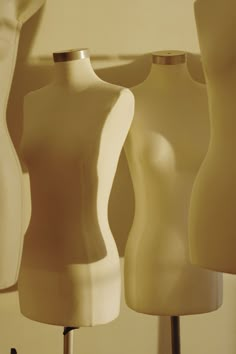 three white mannequins sitting on top of a table