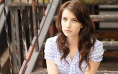 a beautiful young woman sitting on top of a set of stairs next to a hand rail