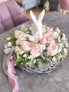 a basket filled with flowers and a white bunny figurine sitting on top of it