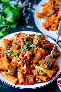 two plates of pasta with meat and parmesan cheese on the side, one has a fork in it