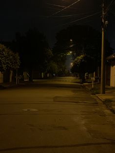 an empty street at night with no cars on the road and power lines above it