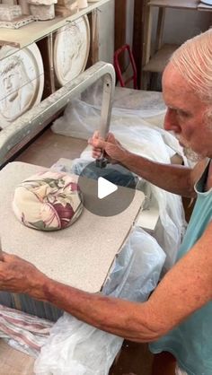 an older man is using a large knife to cut a cake