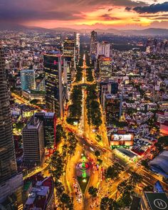 an aerial view of a city at night with the sun setting in the distance and cars driving on the road