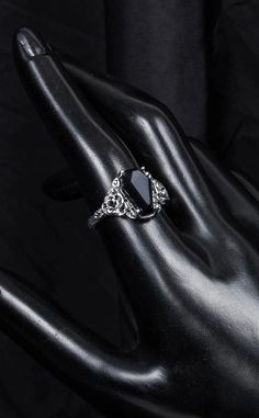 "I'll love you to the tomb and back." Unleash your inner gothic glamour with this stunning ring shaped like a coffin, with the centre featuring a gorgeous black gem, making for a beautifully intricate and unique addition to any outfit. Details: Material: Zinc Alloy Measurements: 1cm wide x 1.5cm tall. Size: Size 7, 8 or 9. Colour: Silver & Black.