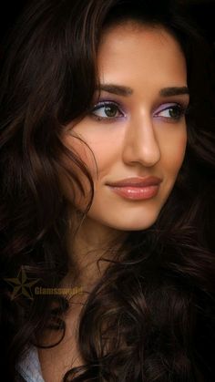 a woman with long dark hair and blue eyeshadow is posing for the camera