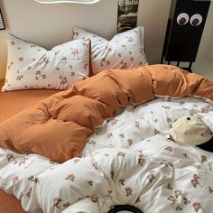 a bed with an orange comforter and pillows