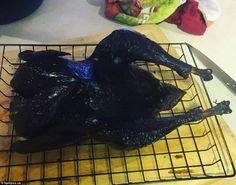 a black bird sitting on top of a metal grate next to a cutting board