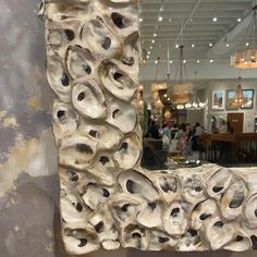 a mirror that is made out of oysters on the side of a wall with people in the background