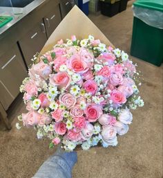 a person holding a bouquet of pink and white flowers in their left hand on the floor